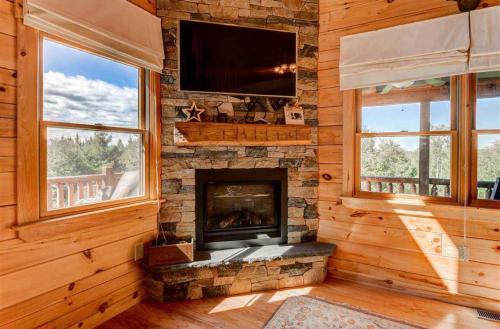 a living room with a fireplace and a tv at OE Beautiful modern log home on 17 acres private views fire pit Ping Pong AC in Whitefield