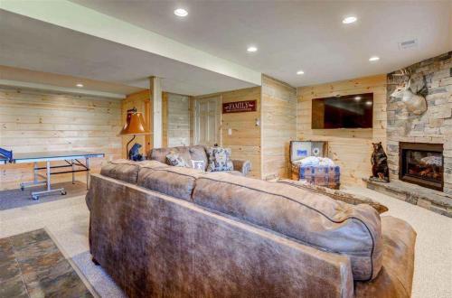 a large leather couch in a room with a fireplace at OE Beautiful modern log home on 17 acres private views fire pit Ping Pong AC in Whitefield