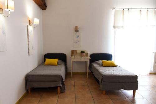 - 2 lits dans une chambre avec une table et des oreillers jaunes dans l'établissement La Bergerie de l'etang, à Montels