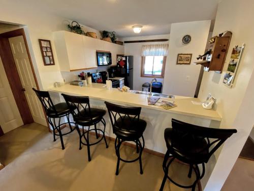 a kitchen with black chairs around a white counter at S4 Ski Slope Views Bretton Woods condo with easy access to Mt Washington Skiing White Mountains in Carroll