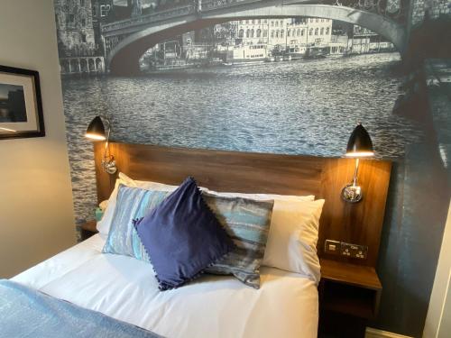 a bedroom with a bed with a painting of a bridge at The Bootham Tavern - York in York