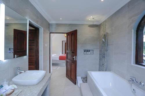 y baño con bañera, lavamanos y bañera. en Mzima Beach Residences - Diani Beach, en Diani Beach