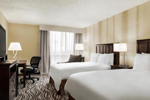a hotel room with two beds and a desk at Radisson Hotel Fort Worth North-Fossil Creek in Fort Worth