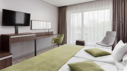 a hotel room with a bed and a desk and a television at Hunguest Hotel Sóstó in Nyíregyháza