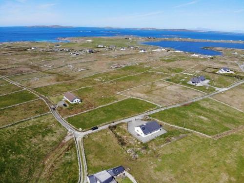 an aerial view of a field with houses and the water at Atlantic Sunset in Aughrus More