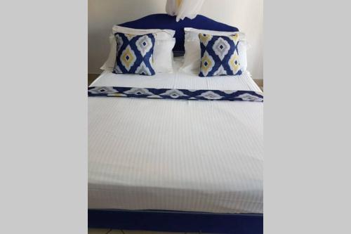 a bed with blue and white sheets and pillows at Dadida‘s Pool Cottage in Diani Beach