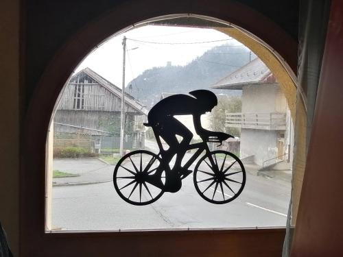 a statue of a person riding a bike through a window at Le Grand Chatelard HÔTEL BAR RESTAURANT in Sainte-Marie-de-Cuines