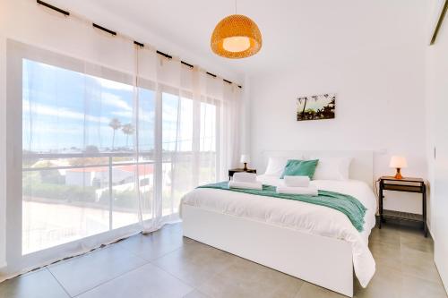 Dormitorio blanco con cama y ventana grande en SEA VIEW LARANJEIRAS, en Quelfes