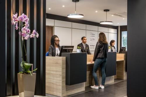 un groupe de personnes debout à un bureau de réception dans l'établissement Citadines La Défense Paris, à Courbevoie