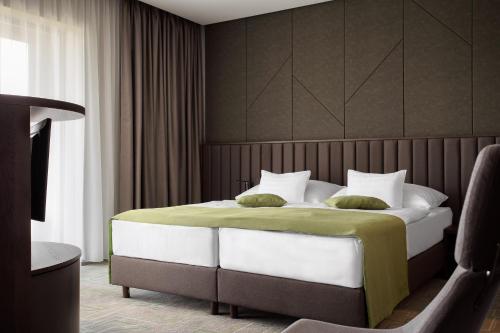 a bedroom with a large bed with green and white pillows at Hunguest Hotel Sóstó in Nyíregyháza