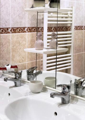 un lavabo de salle de bain avec deux robinets et un miroir dans l'établissement Villa Marguerite, à Coutras