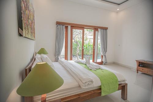 a bedroom with a bed with a green lamp and a window at Villa Paradise Seminyak in Seminyak