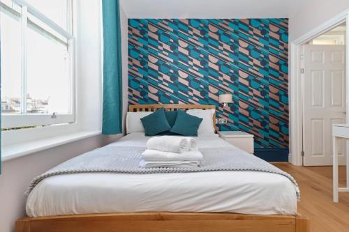 a bedroom with a bed with a blue accent wall at Ravilious in Eastbourne