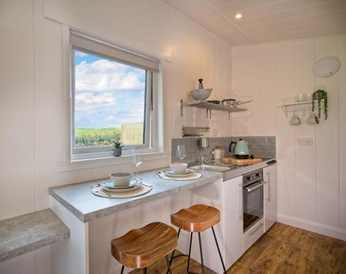 cocina con encimera con 2 taburetes y ventana en The Pond Lodges Barstobrick en Ringford