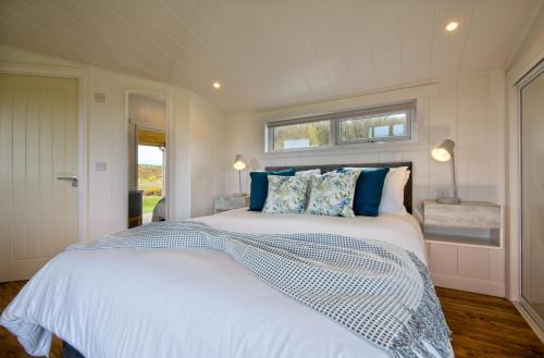 una camera da letto con un grande letto bianco con cuscini blu di The Pond Lodges Barstobrick a Ringford