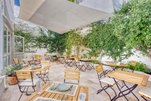 a patio with tables and chairs and trees at Can Alberti 1740 Boutique Hotel in Mahón