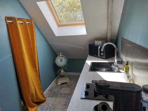 een keuken met een wastafel en een klok aan de muur bij L'atelier les hortensias in Marquise
