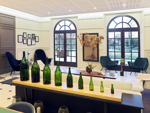 Les Chambres du Champagne Collery في آي: مجموعة من زجاجات النبيذ على طاولة في غرفة