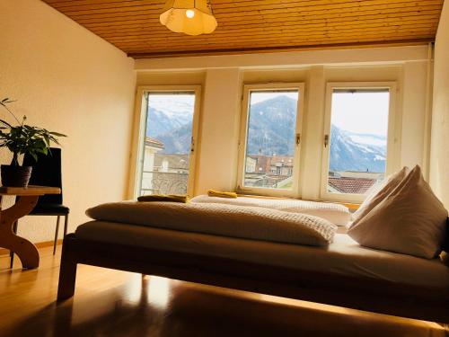 a room with two beds in front of two windows at central beauty scenery apartment in Interlaken