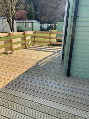 a wooden deck next to a house with a fence at The Roecliffe 54 in Dunoon