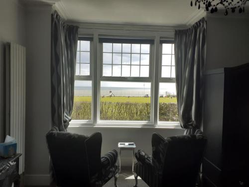 a room with two chairs and a window with a field at South Beach B & B in Lowestoft