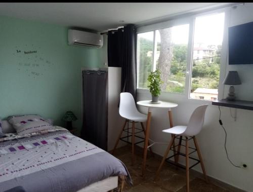 a bedroom with a bed and a table and a window at Studio d'environ 20m2, piscine, vue mer, pour 2 personnes in Marseille