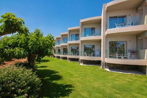 a row of apartment buildings with a green yard at Aeolos Beach Resort in Malia