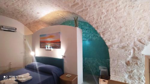 sala de estar con sofá azul y pared en La Volta del Conte-Holiday Home Centro Storico en Cisternino