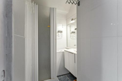 une salle de bain blanche avec une douche et un lavabo dans l'établissement Appartement charmant à Antibes, 33 m², piscine partagée, à Antibes