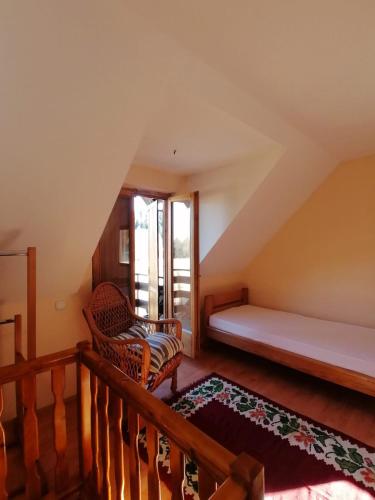 a attic room with a bed and a chair at Apartmani Sokolski odmor in Bajina Bašta
