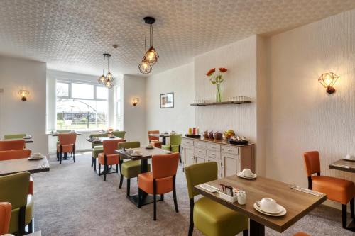 a restaurant with tables and chairs in a room at Palm Court in Skegness