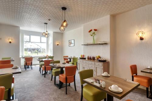 a restaurant with tables and chairs in a room at Palm Court, Seafront Accommodation in Skegness