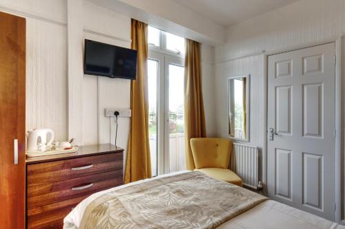 a bedroom with a bed and a chair and a window at Palm Court in Skegness