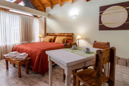 1 dormitorio con 1 cama, mesa y sillas en Lagos del Sur en San Carlos de Bariloche