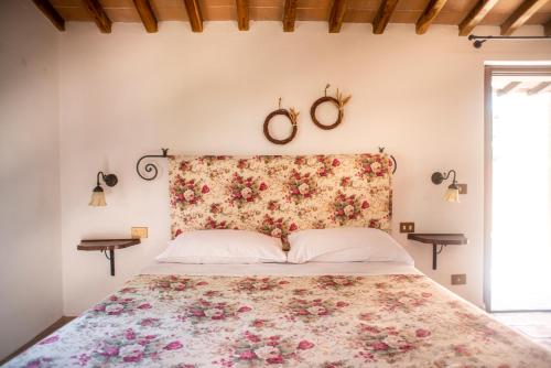 a bedroom with a large bed with a floral headboard at Agriturismo Pieve Sprenna in Buonconvento