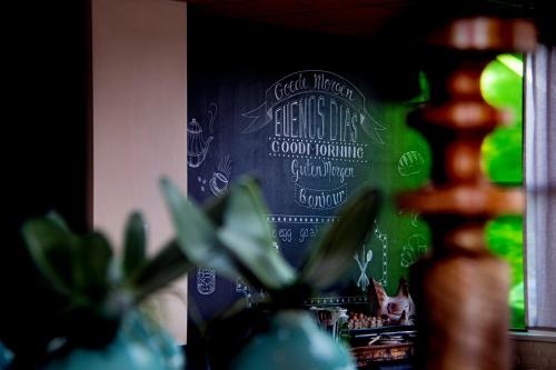 Eine Tafel mit einer Katze vor einer Pflanze in der Unterkunft Hotel Umberto in Wijchen