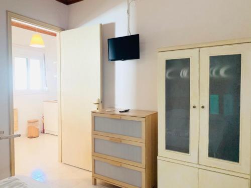 a bedroom with a dresser and a tv on the wall at Seaside Bungalows Petalidi in Petalidhion