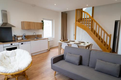 a living room with a couch and a kitchen with a staircase at Joli loft spacieux de 100m2 pour 10pers in Saumur