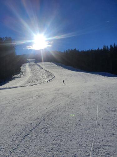 a person skiing down a snow covered slope with the sun at Apartment Diana in Bad Goisern