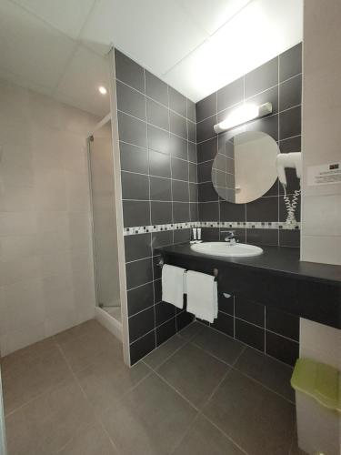 ein Bad mit einem Waschbecken und einem Spiegel in der Unterkunft La Croix Blanche in Beaurepaire-en-Bresse