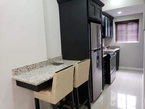 a kitchen with a counter with chairs and a refrigerator at Christar Villas Hotel in Kingston