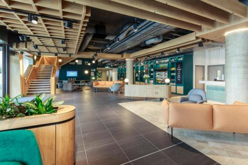 an office lobby with couches and chairs and stairs at Novotel Cambridge North in Cambridge