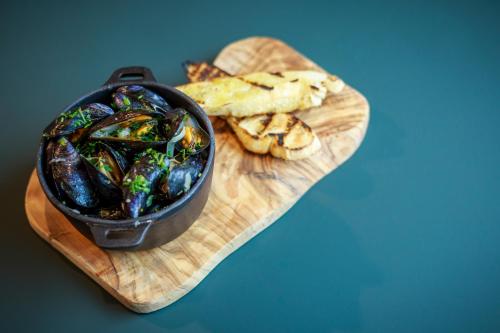 a wooden cutting board with a bowl of food and crackers at Novotel Cambridge North in Cambridge