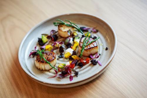 a plate of food with scallops on a table at Novotel Cambridge North in Cambridge