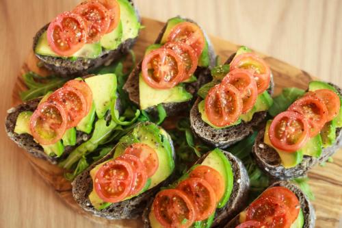 a group of sandwiches with tomatoes on a wooden plate at Novotel Cambridge North in Cambridge