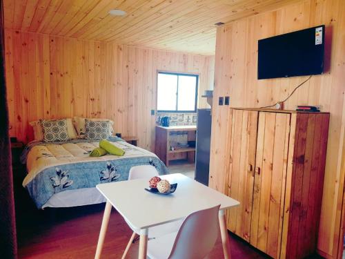 um quarto com uma cama, uma mesa e uma televisão em ELUNEY Pichilemu em Pichilemu