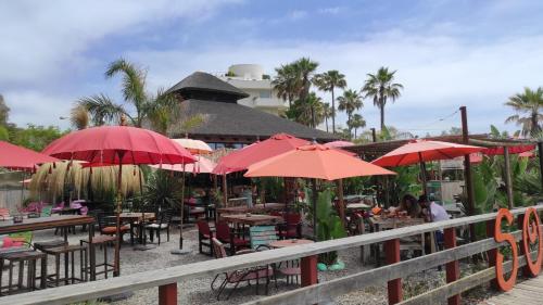 a restaurant with tables and red umbrellas at Casa Cachita 2-Confortable Estudio a pie de playa in Estepona