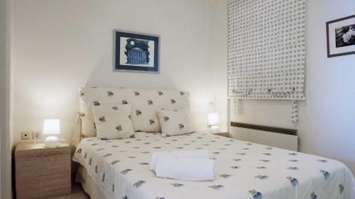 a small bedroom with a bed with a white bedspread at Thyme Glyfada Beach in Glyfada