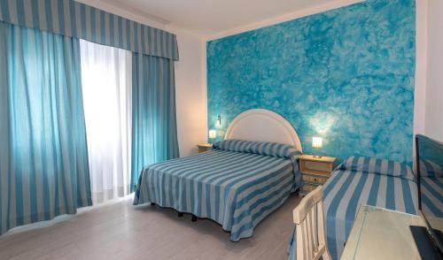 a bedroom with a bed and a mirror and a window at Hotel Paolina in Lido di Jesolo