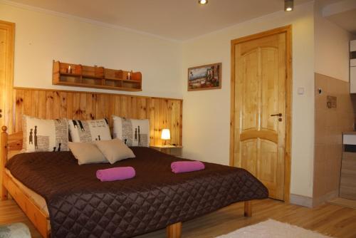 a bedroom with a large bed with pink pillows on it at Harmónia Apartmanház in Hajdúszoboszló